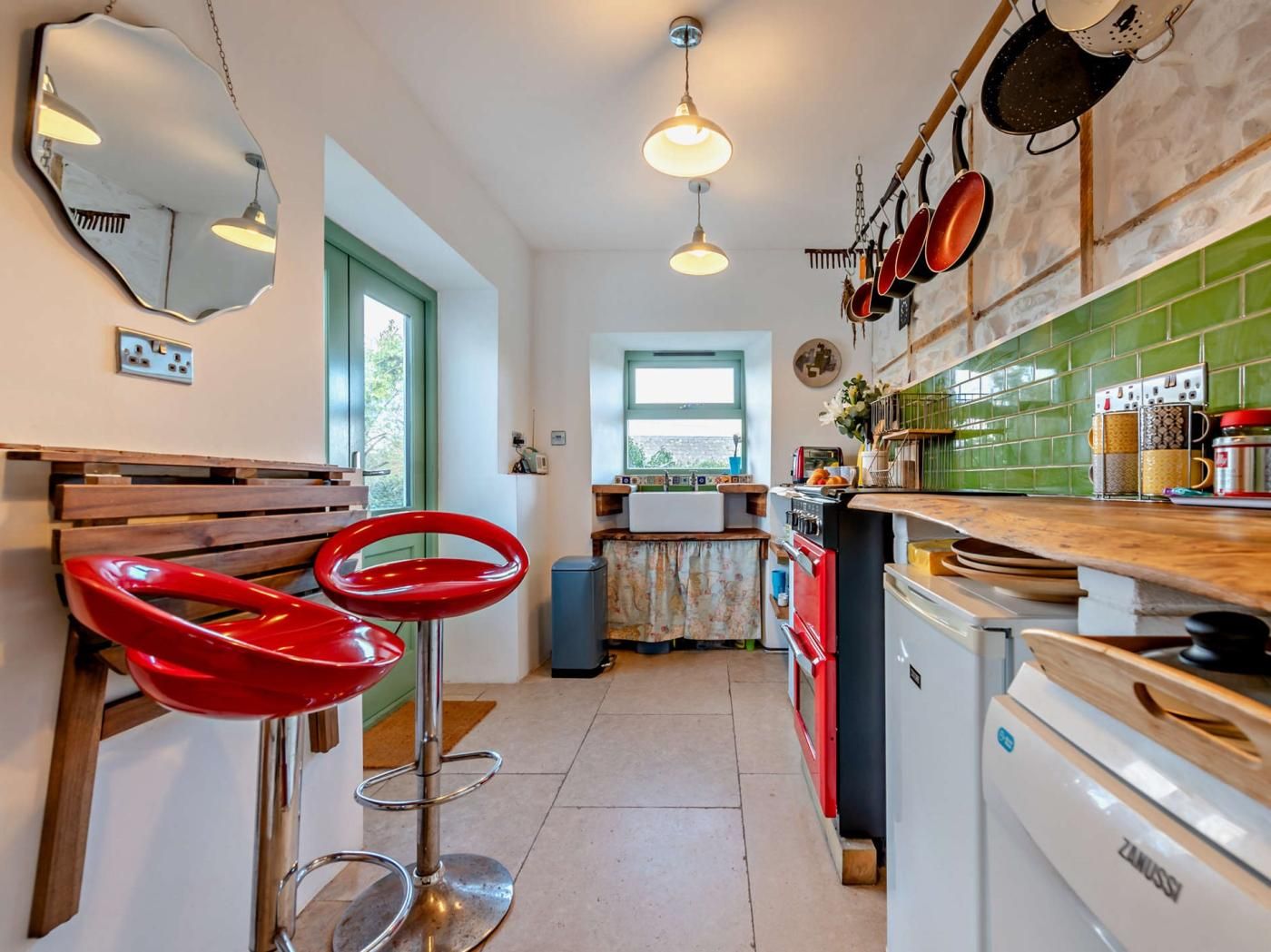 A kitchen with a red bar stool, a white dishwasher, and a green tiled backsplash.
