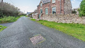 A stone house with a paved driveway, a grassy area, and a clear sky. - 2 Bed in Haverfordwest (oc-93577) (Marloes)