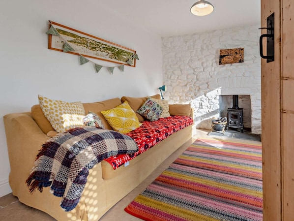 A cozy living room with a sofa, colorful pillows, a patterned blanket, a stone wall, and a fireplace. - 2 Bed in Haverfordwest (oc-93577) (Marloes)