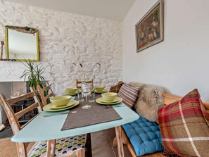 A dining area with a stone wall, a table set with green plates, and a sofa with a plaid cushion.