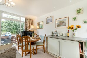 A dining area with a table, chairs, a television, and a kitchen counter with a toaster, kettle, and wine bottle. - 2 Bed in Nolton Haven (oc-fb098) (Nolton Haven)