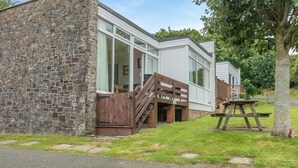Ein modernes Gebäude mit einer Stein-Fassade, großen Fenstern und einer Holzterrasse.
