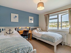 Ein Schlafzimmer mit zwei Betten, einem Schreibtisch und Blick aufs Meer.