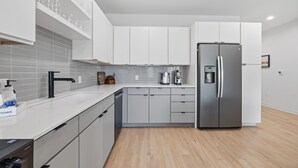 A modern kitchen with white cabinets, a stainless steel refrigerator, and a tiled backsplash. - 2BR South Congress Condo for 6, Near DT! (Austin)