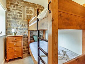 A bunk bed room with a stone wall, a wooden dresser, and a lamp. - 4 Bed in Matlock (oc-93830) (Crich)