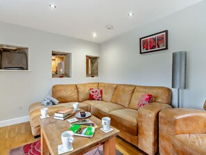 A modern living room with a leather sofa, a coffee table with books and cups, and a framed picture on the wall. - 4 Bed in Matlock (oc-93830) (Crich)