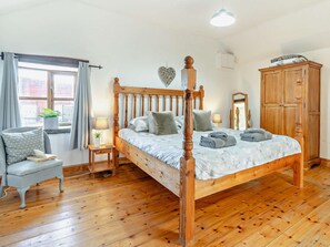A four-poster bed with a wooden frame, a bedside table, a chair, a wardrobe, and a window with curtains. - 3 Bed in Swansea (oc-93942) (Southgate)