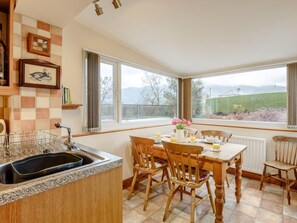 Eine Küche mit Granit Arbeitsplatte, Spüle und einem Essbereich mit Holztischen und einem Tisch.