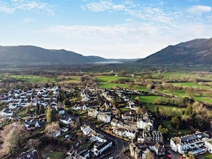 Une ville traversée par une rue principale, bordée de maisons et entourée de verdure.