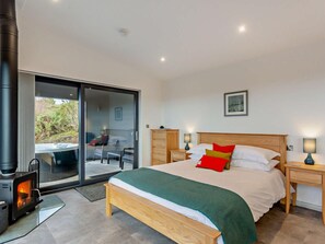 A bedroom with a bed, a wooden headboard, a nightstand, a lamp, and a fireplace.