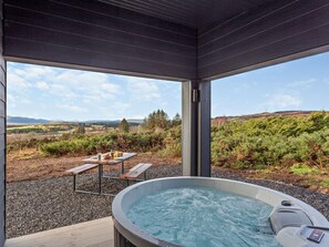 A hot tub with a table and benches, surrounded by gravel, with a view of a landscape. - 1 Bed in Ardgay (oc-90471) (Migdale)