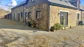Ein Gebäude aus Stein mit einem geneigten Dach, mehreren Fenstern und einer Schotterauffahrt.