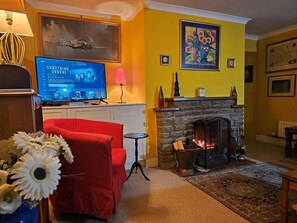 Un salon avec une cheminée, un téléviseur et un fauteuil rouge.