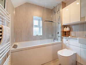 Moderni kylpyhuone, jossa on kylpyamme, wc ja ikkuna.