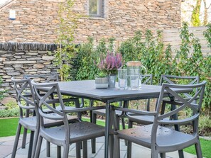 Eine Terrasse mit Steinmauer, Tisch und Stühlen sowie einem Blumentopf.