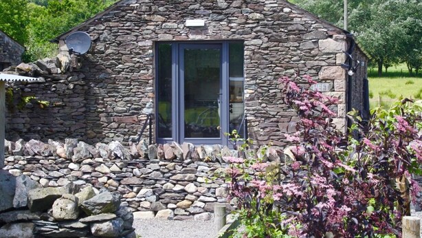 A stone cottage with a window, a door, and a satellite dish. - 1 Bed in Penrith (oc-94068) (Ullswater)