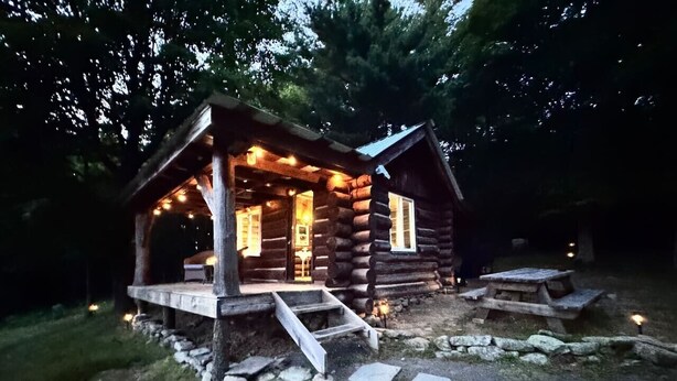 Una cabana de fusta amb un porxo, escales de pedra i una taula de pícnic.