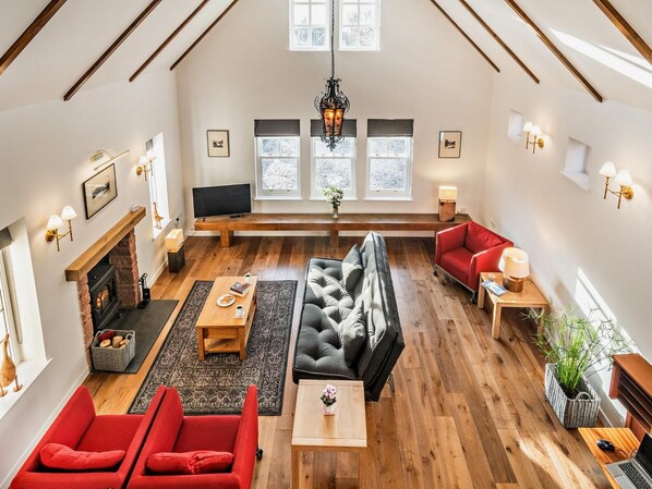 A spacious living room with a fireplace, multiple seating options, and large windows allowing natural light. - 1 Bed in Helensburgh (oc-94081) (Helensburgh)