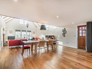 A spacious living area with a dining table, red seating, and a large window. - 1 Bed in Helensburgh (oc-94081) (Helensburgh)