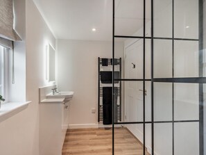 A modern bathroom with a white sink, mirror, and wooden flooring. - 1 Bed in Helensburgh (oc-94081) (Helensburgh)