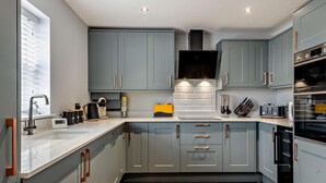A modern kitchen with grey cabinets, a built-in oven, and a coffee machine. - 2 Bed in Cromer (oc-91297) (Cromer)
