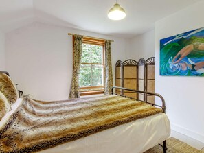 A bedroom with a bed, a window with curtains, a painting on the wall, and a ceiling light.