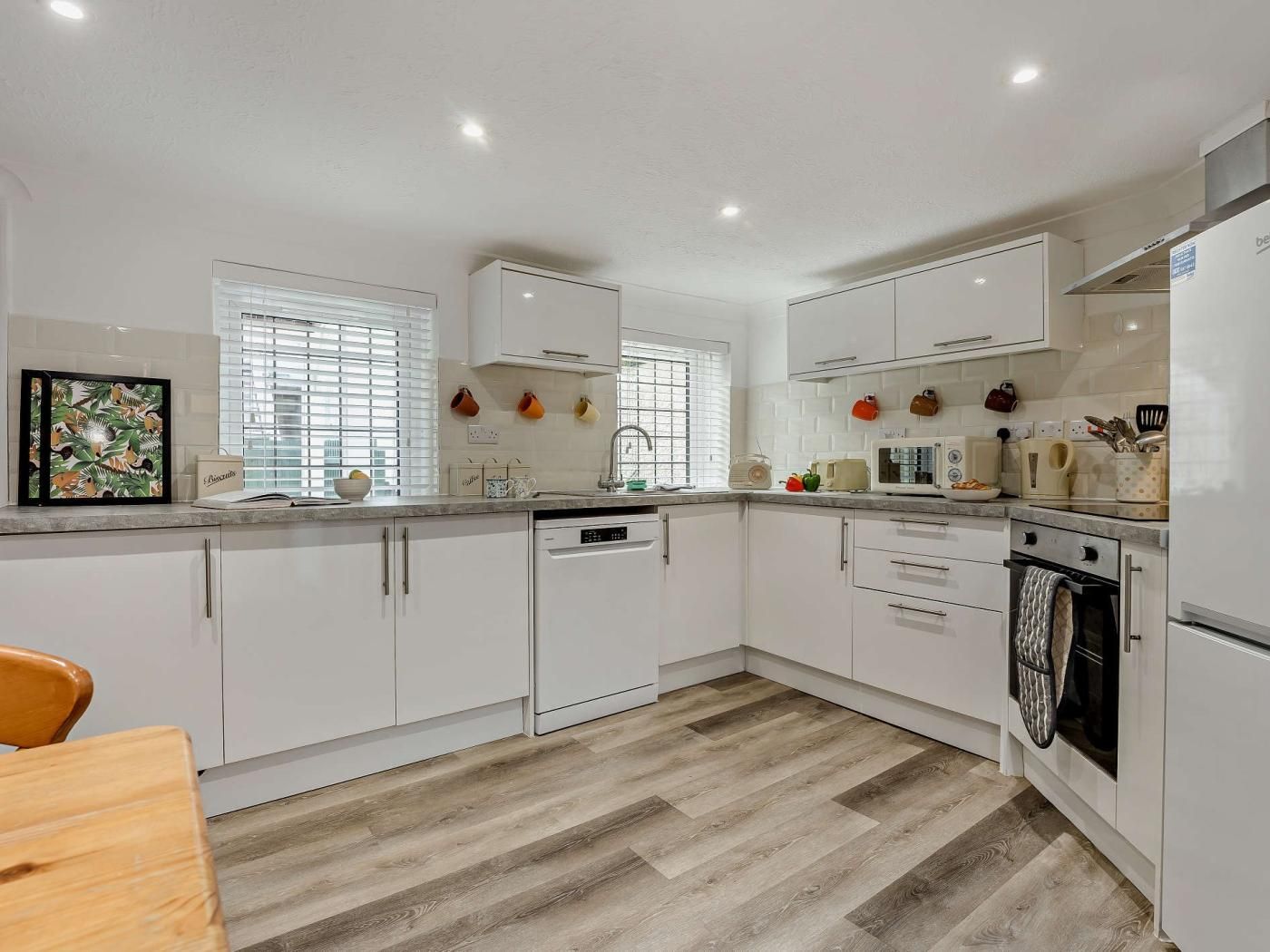 A modern kitchen with white cabinetry, a dishwasher, a microwave, and a stove.