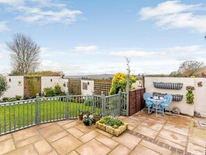 A patio with a table and chairs, a garden, and a white wall with a window. - 1 Bed in Worthing (oc-80539) (Worthing)