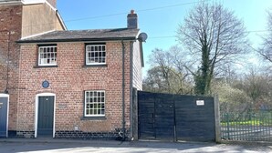 A brick building with a gated entrance, a door, and a window. - 2 Bed in Llanidloes (oc-94088) (Llanidloes)