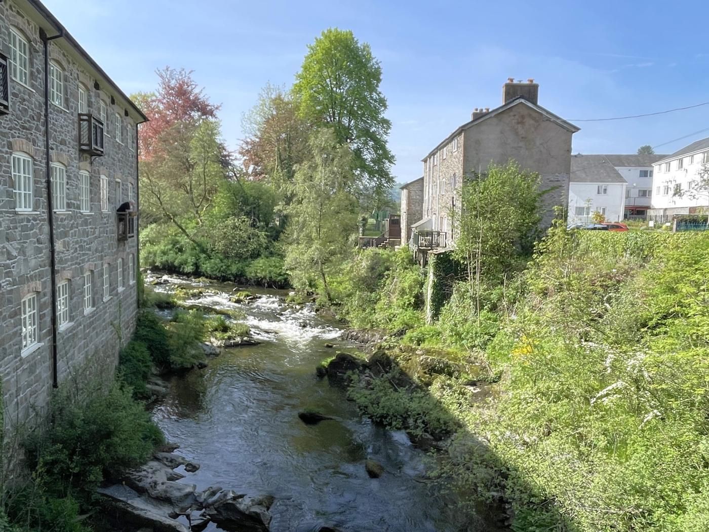 A stone building with a river running through a garden.