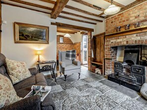 A cozy living room with a fireplace, a painting on the wall, and a comfortable sofa.