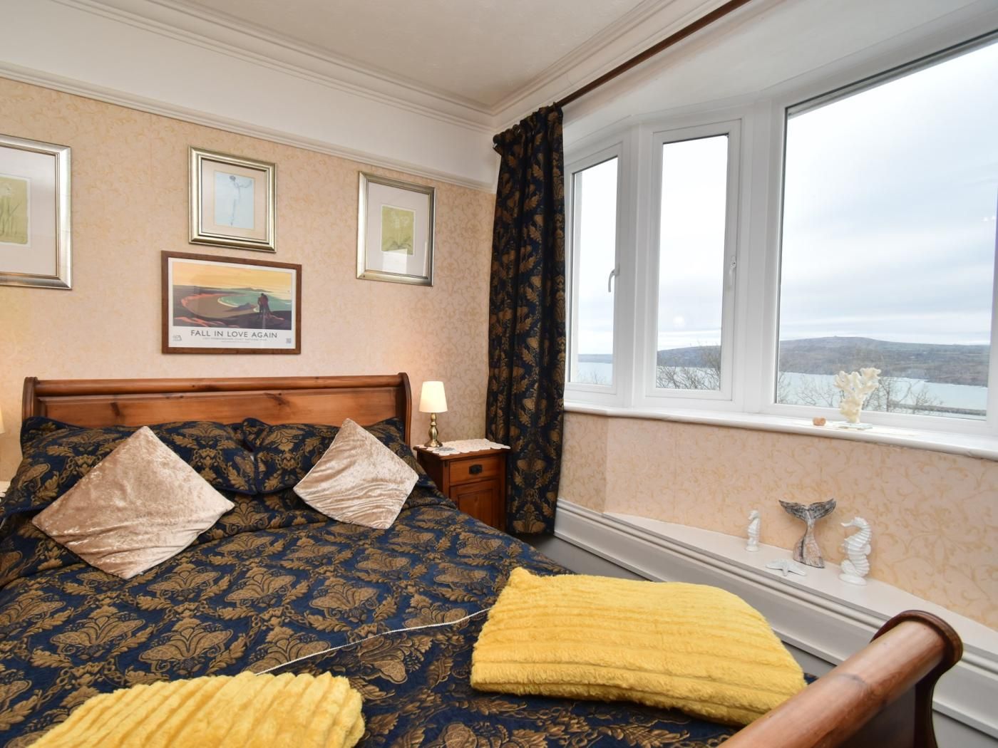 A bedroom with a bed, a nightstand, a window with a view, and wall-mounted artwork.