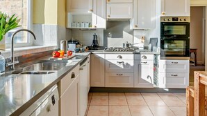 A modern kitchen with white cabinetry, a stainless steel sink, and a built-in oven. - 4 Bed in Alnwick (oc-cn155) (Alnmouth)