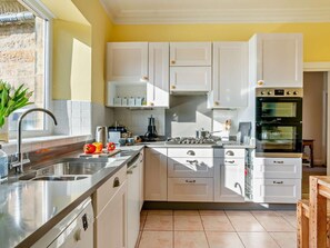 Eine moderne Küche mit weißen Schränken, einer Edelstahl-Spüle und einem eingebauten Backofen.