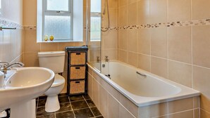 Ein Badezimmer mit Badewanne, Waschbecken, Toilette und einem Fenster.