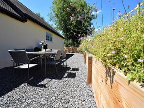 Een terras met een tafel en stoelen, een houten hek en een grindpad.