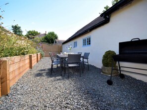 Eine Terrasse mit Tisch, Stühlen und Grill, mit Kiesboden.