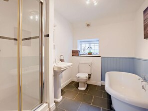 Een badkamer met een douchecabine van glas, een wastafel op een voetstuk, een toilet en een vrijstaand bad.