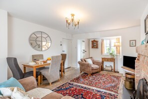 Ein geräumiges Wohnzimmer mit Kamin, Essbereich und einer gemütlichen Sitzecke mit einem gemusterten Teppich.