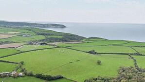 Ländliche Landschaft mit Feldern, einem kleinen Haus und einem Gewässer.