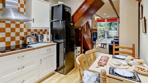 A compact kitchen with a black refrigerator, white cabinets, and a wooden staircase leading to a dining area. - 3 Bed in Skipton (oc-93485) (Embsay)