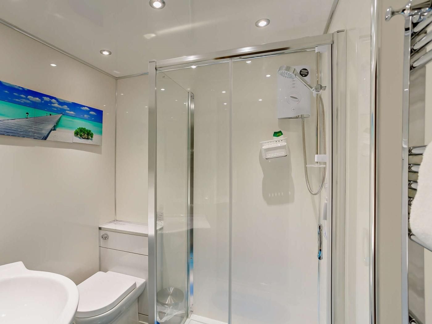 Un baño moderno con ducha envuelta en vidrio, inodoro y lavamanos.