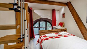 A bedroom with a wooden bed, a window with a red curtain, and a wooden ceiling beam. - 3 Bed in Skipton (oc-93485) (Embsay)