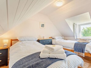 Ein Schlafzimmer mit zwei Betten, einem Nachttisch, einer Lampe, einem Fenster mit Vorhängen und einem Bild an der Wand.