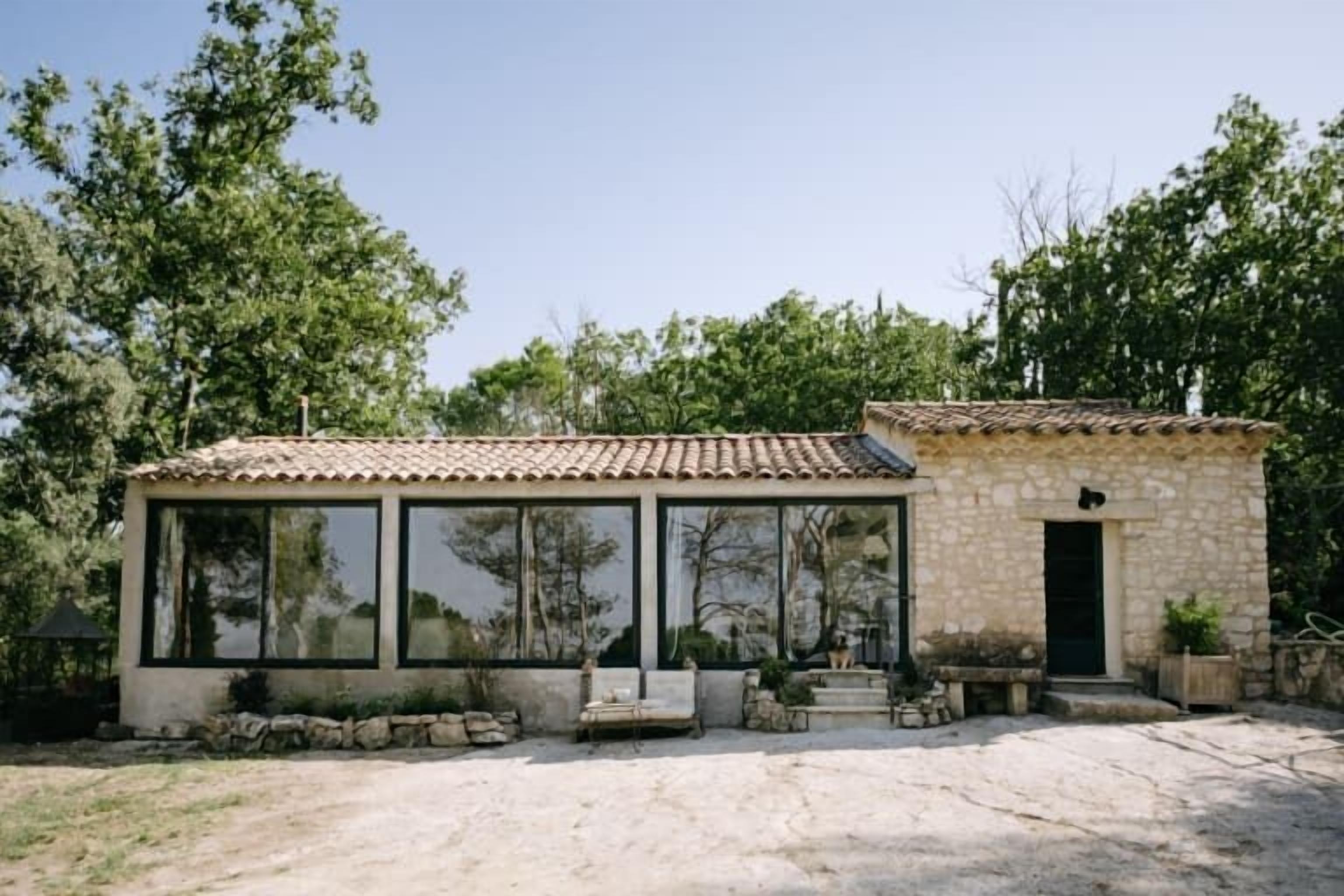 Un bâtiment en pierre doté de grandes fenêtres, d’un toit recouvert de tuiles et d’un petit porche.