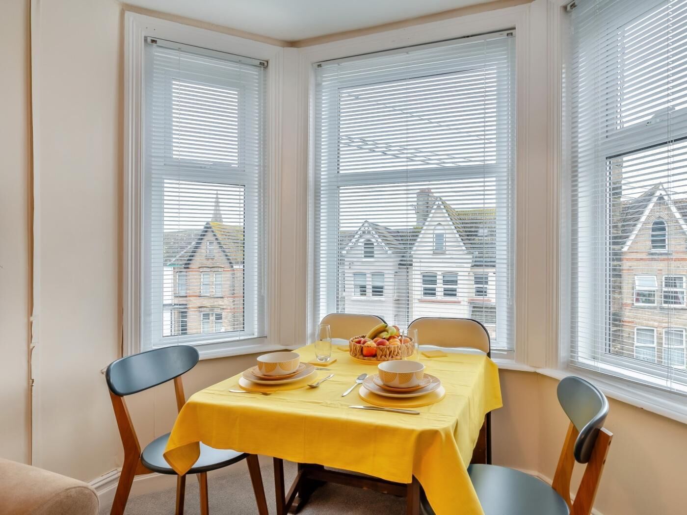 En matplats med ett bord dukat för två personer, två stolar och utsikt över byggnader genom fönstren.