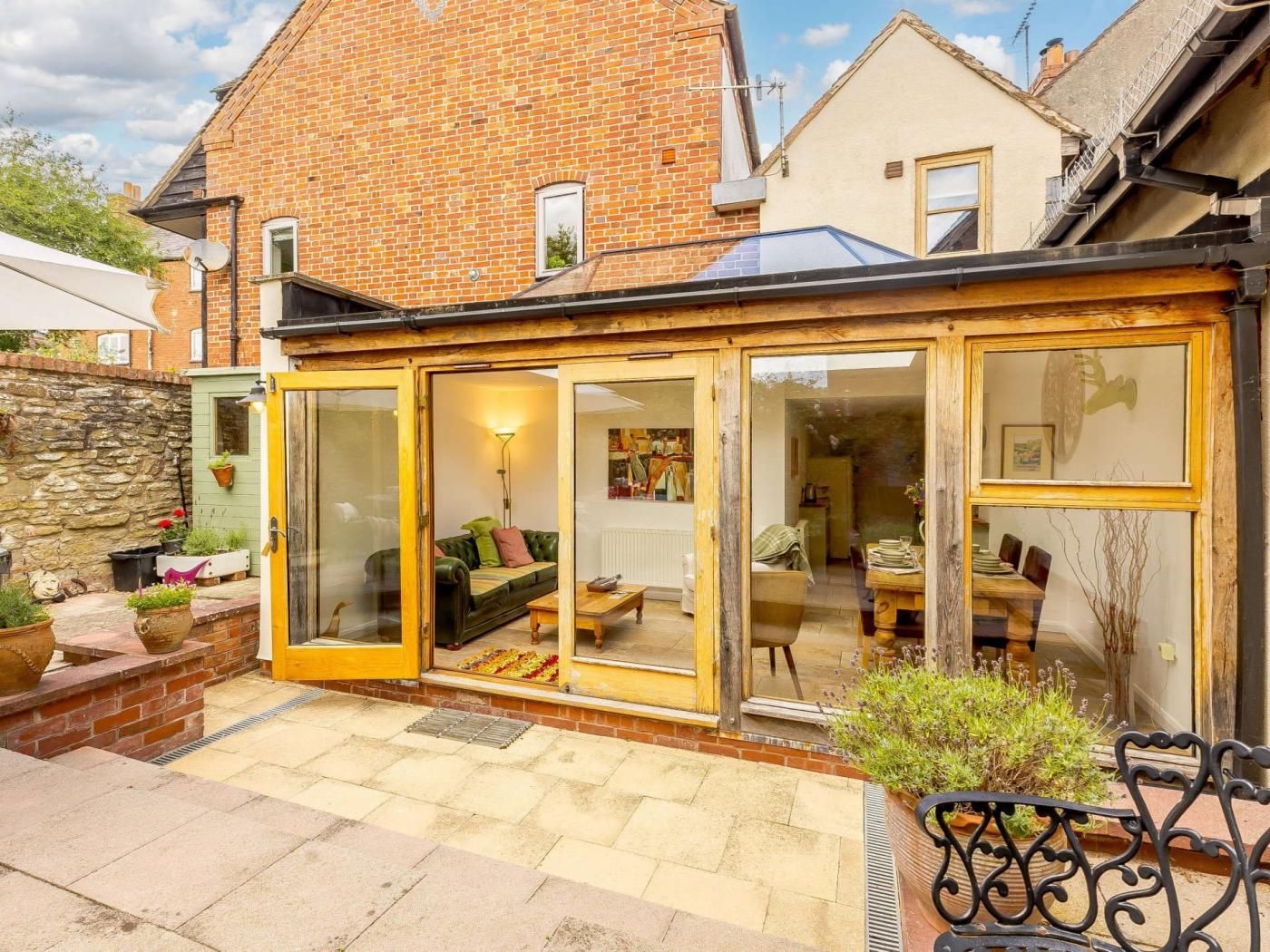 A house with a conservatory, a brick exterior, and a stone wall.