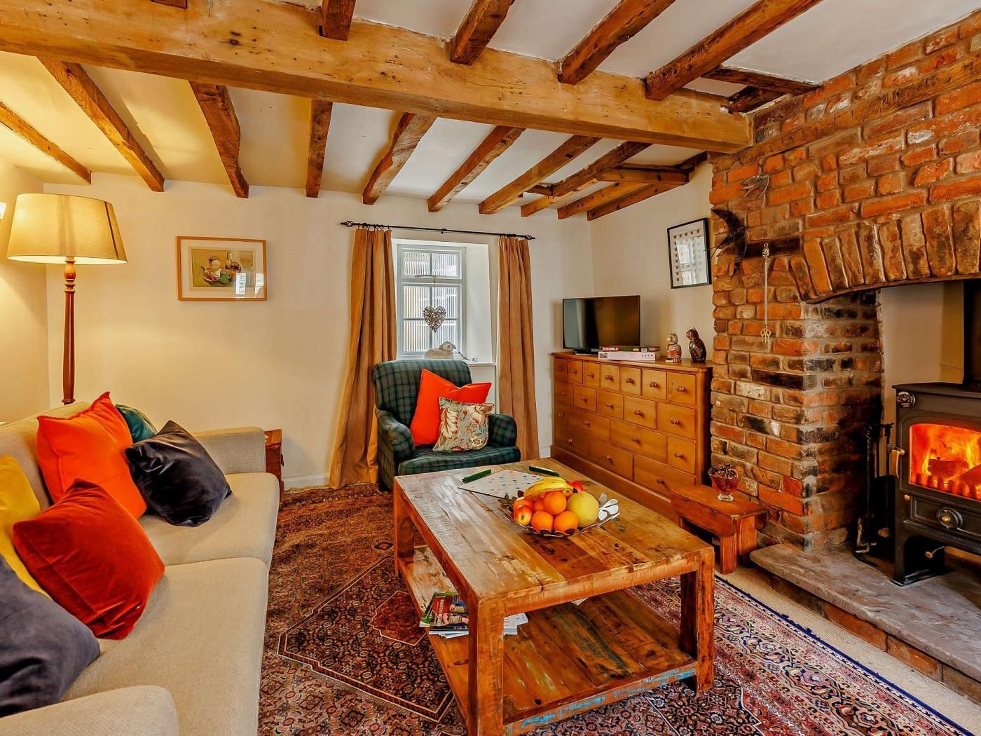 Un salón acogedor con chimenea, un sofá, una mesa de centro con fruta y un televisor.