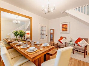 A dining area with a wooden table set for four, a large mirror, and a chandelier. - 4 Bed in Morpeth (oc-93510) (Amble)