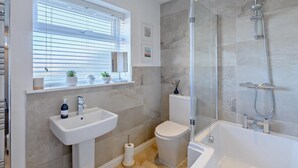 Ein modernes Badezimmer mit Waschbecken, Toilette, Dusche und Fenster.